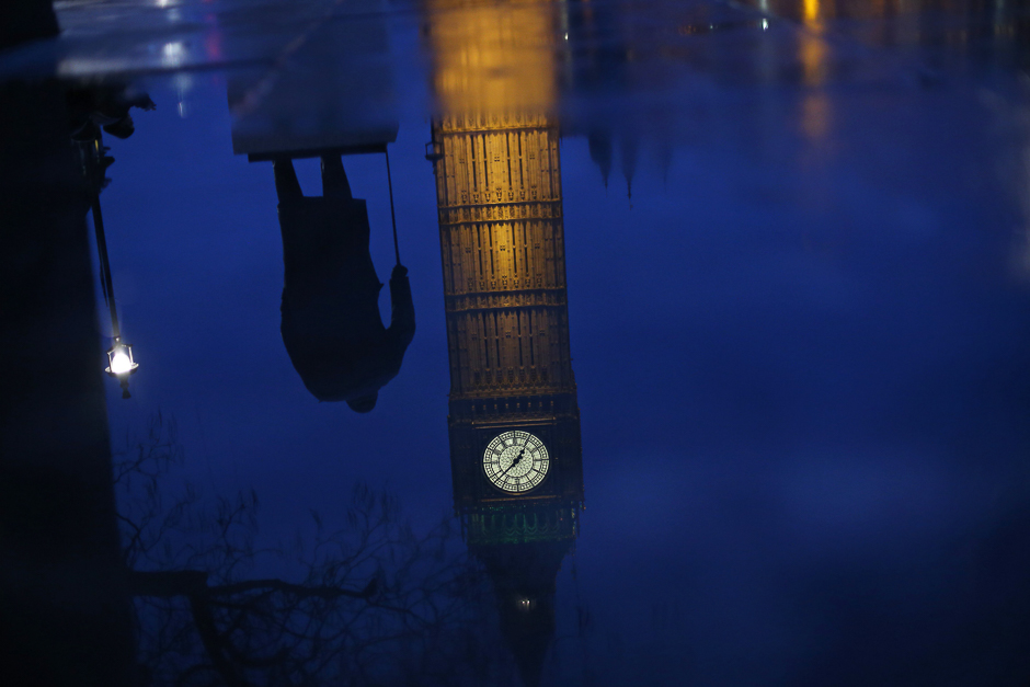 The Big Ben clock face and the Elizabeth Tower and statue of Winston Churchill are seen reflected in a puddle in Parliament Square, central London. PHOTO: AFP