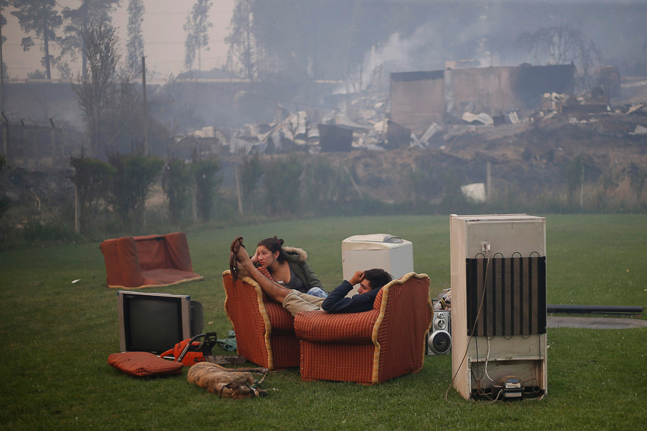 A young couple rest in a football field after a forest fire devastated Santa Olga, 240 kilometres south of Santiago. PHOTO: AFP