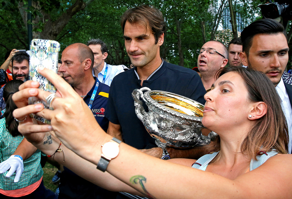 A woman takes a selfie with Switzerland's Roger Federer as he holds the trophy during a photo call the morning after he won the Men's singles final at the Australian Open tennis tournament in Melbourne, Australia. PHOTO: REUTERS