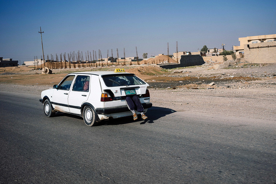 An Iraqi man rides in the trunk of a taxi in eastern Mosul. PHOTO: AFP