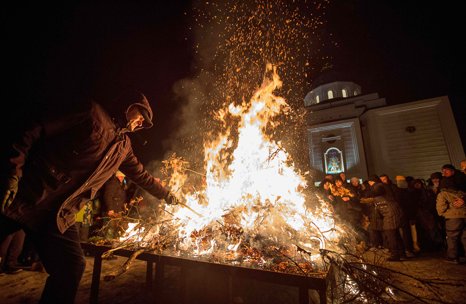 A man burns dried oak branches, the Yule log symbol for the Orthodox Christmas Eve in front of Saint Demetrios church in Belgrade during the Christmas Orthodox Day. PHOTO: AFP