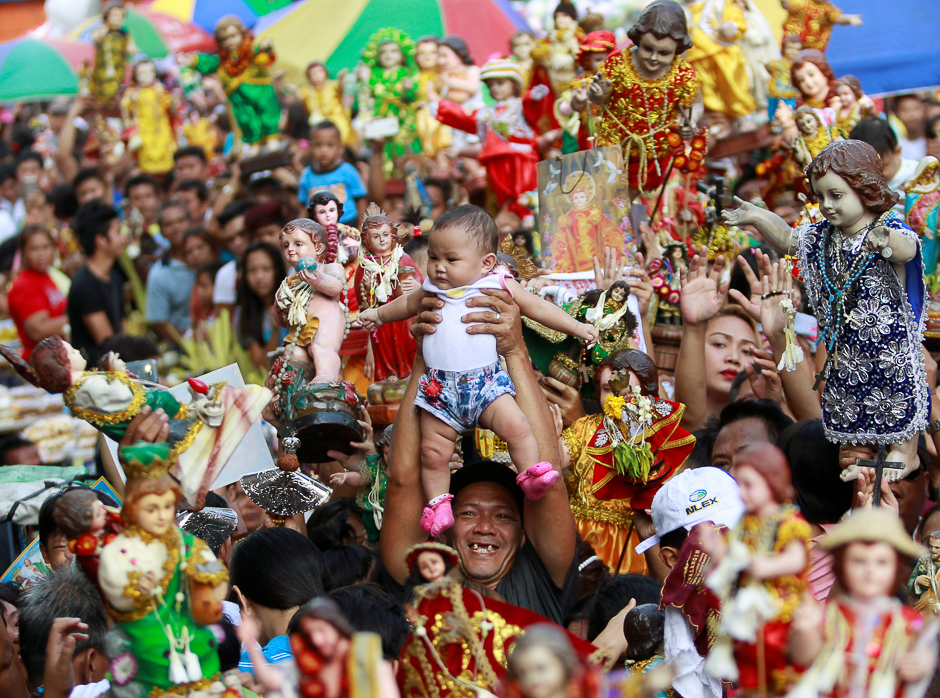 A devotee carries his child to be blessed by the lay minister with holy water during the annual feast of Sto. Nino (Holy Child Jesus) in Manila, Philippines. PHOTO: REUTERS
