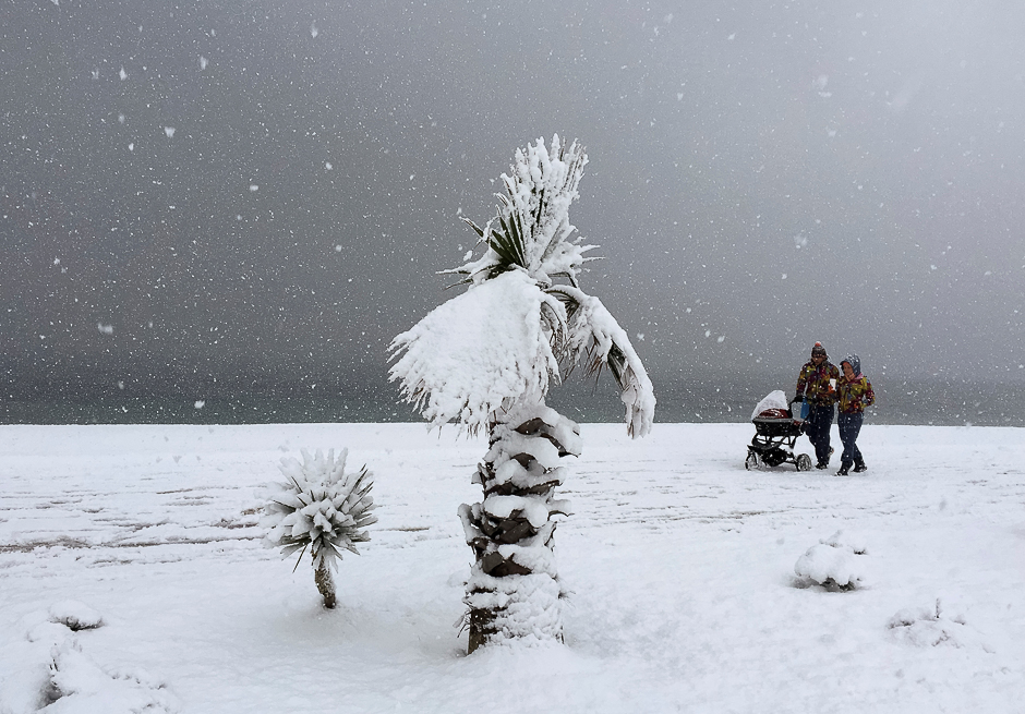 A couple walks with a pram along an embankment under a heavy snow fall in Sochi, Russia. PHOTO: REUTERS