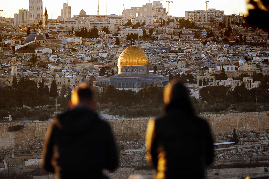 Two persons watch the sun setting on the Old City of Jerusalem, with the Muslim mosque of the Dome of the Rock in the center. PHOTO: AFP