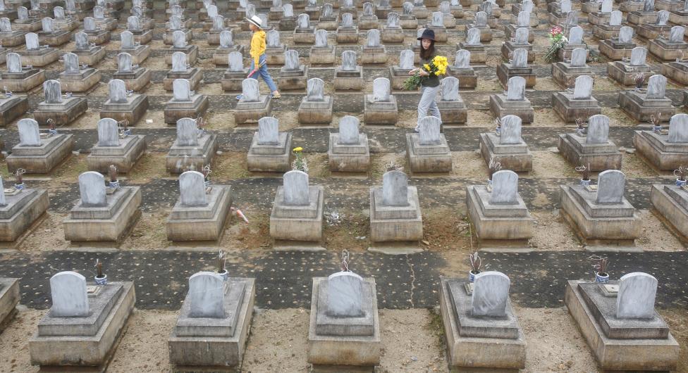 Kim Chi Tran (R), next to her son Thai An, looks for the grave of a relative killed during the Vietnam War, ahead of the Vietnamese lunar new year (or Tet) when it is tradition to visit the graves of loved ones, at the Viet-Laos national cemetery in Nghe An province, Vietnam. REUTERS/Kham