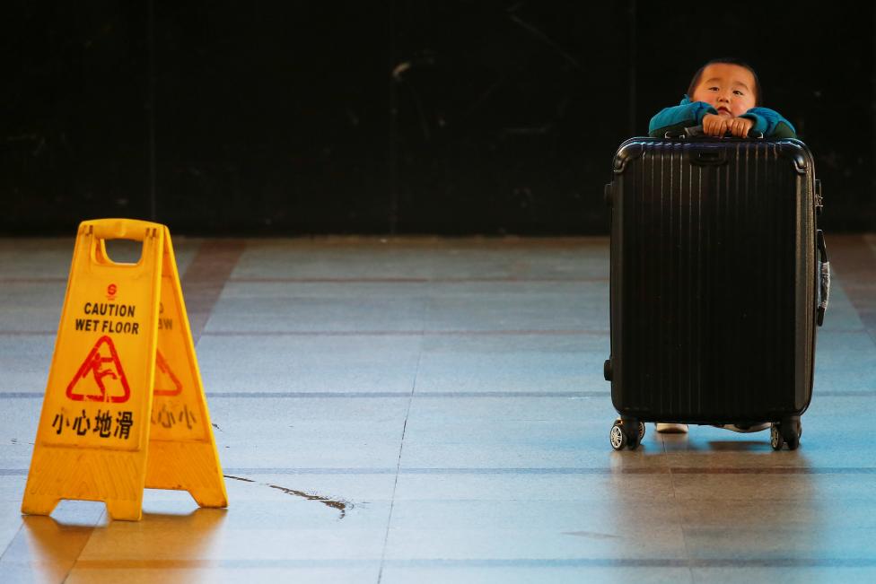 A boy tries to lift a suitcase at the departure hall of the Beijing Railway Station in central Beijing. REUTERS/Damir Sagolj
