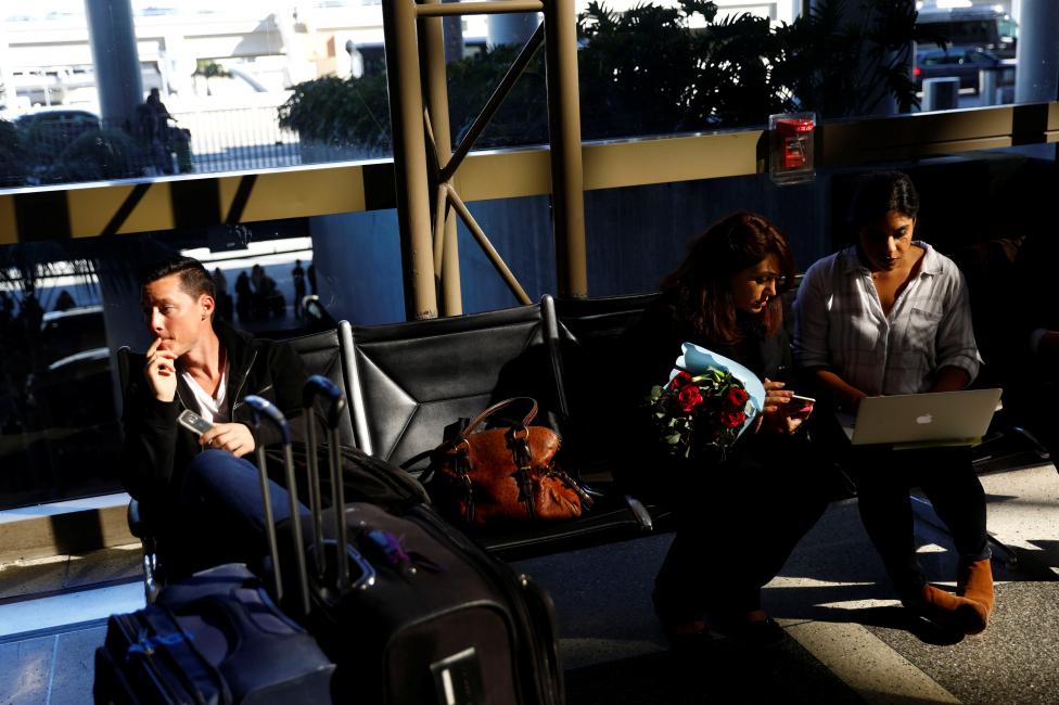 A passenger waits for his girlfriend, who was born in Iran but holds a Canadian passport and had not been allowed entry to the US after vacationing in Thailand, (L), as an attorney works to help family members of Sarah Saedian, (centre R), both affected by the travel ban at Los Angeles International Airport (LAX) in Los Angeles. REUTERS/Patrick T. Fallon