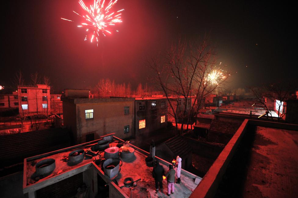People watch firework explode from a rooftop on the eve of the Chinese Lunar New Year, or the Spring Festival, in Mengcheng, Anhui province, China. REUTERS/Stringer