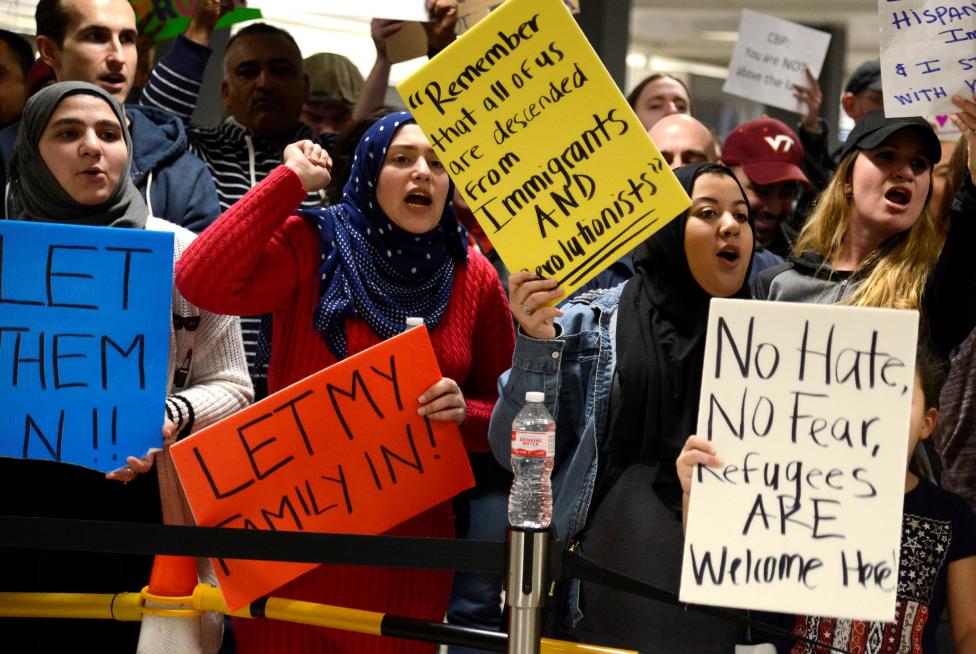 Dozens of pro-immigration demonstrators cheer and hold signs as international passengers arrive at Dulles International Airport, to protest President Donald Trump's executive order barring visitors, refugees and immigrants from certain countries to the United States, in Chantilly, Virginia, in suburban Washington. REUTERS/Mike Theiler
