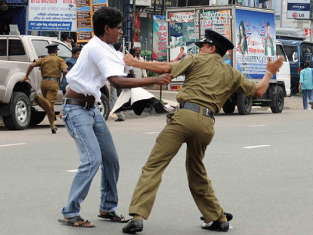 Sri Lankan police officer beating a protester on October 29, 2015. PHOTO: AFP 