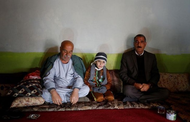 Ayman sits beside his uncle Samir Rasho Khalaf (L) after he was returned to his Yazidi family in Duhok, Iraq, January 31, 2017. PHOTO: REUTERS