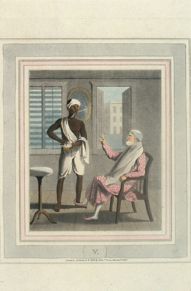 “An Indian servant holds a straight razor in his mouth while he prepares the shaving foam for his British master.”