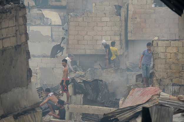 Residents collect recyclable materials amongst the ruins of their houses, which were gutted by a fire overnight, in an informal settlers area near the south harbour port in Manila on February 8, 2017. PHOTO: AFP