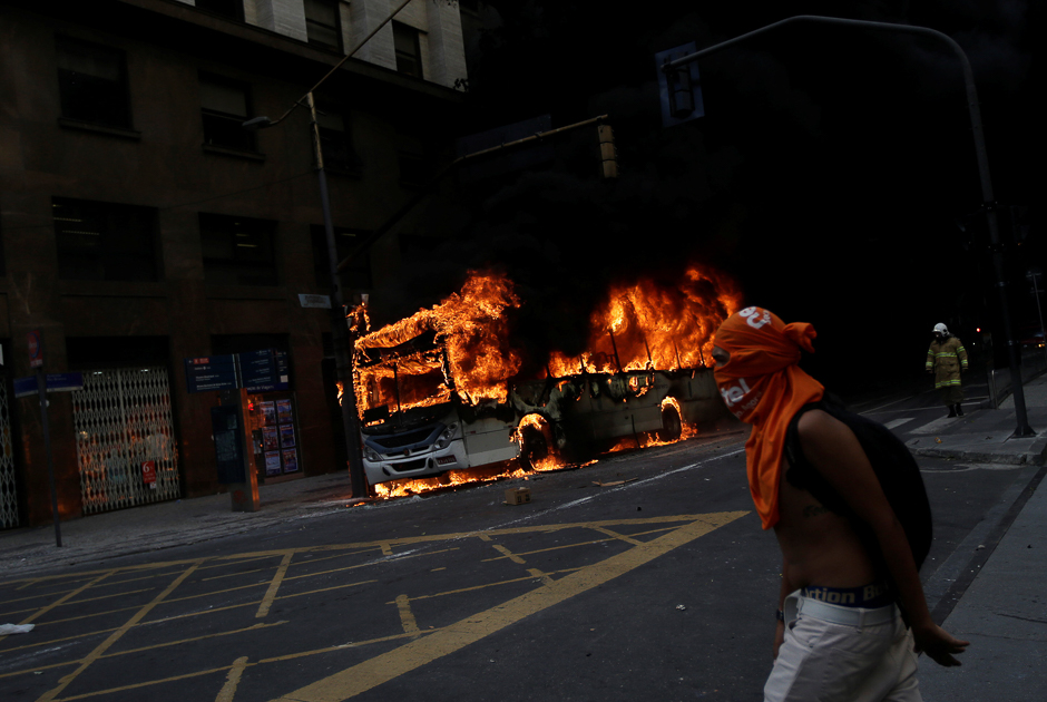 An anti-government demonstrator walks past a bus burning after a clash with riot policemen, during a protest against the Rio de Janeiro state government and a plan that will limit public spending, next to the State Assembly of Rio de Janeiro, Brazil. PHOTO: REUTERS