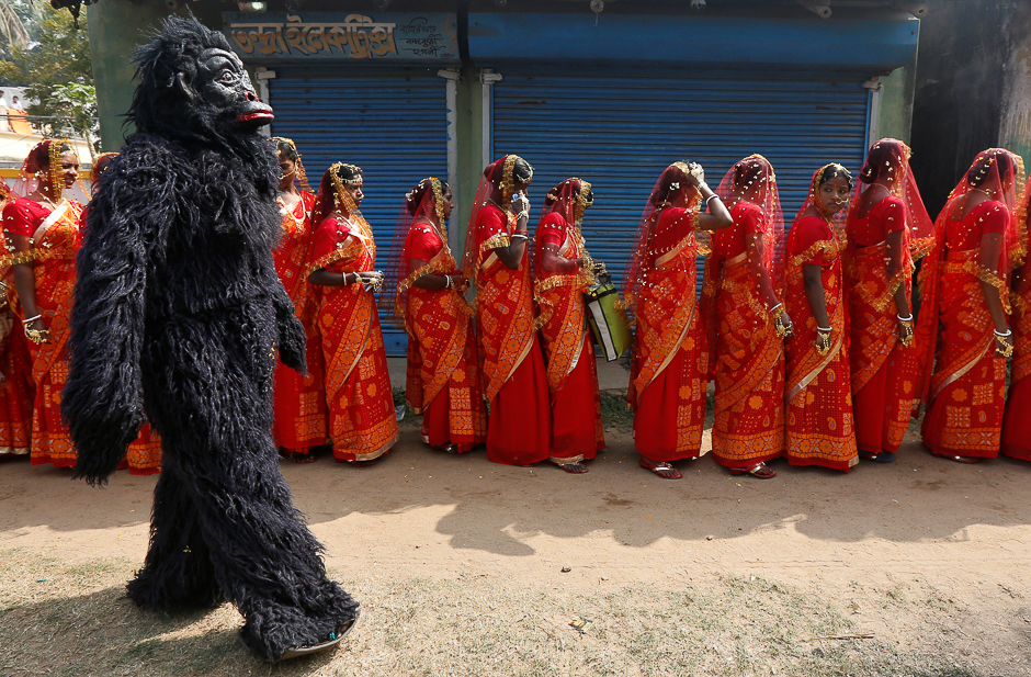 A performer dressed in a chimpanzee costume walks past brides as they arrive at a mass marriage ceremony in which, according to its organisers, 109 tribal, Muslim and Hindu couples from various villages across the state took their wedding vows, at Bahirkhand village, north of Kolkata, India. PHOTO: REUTERS
