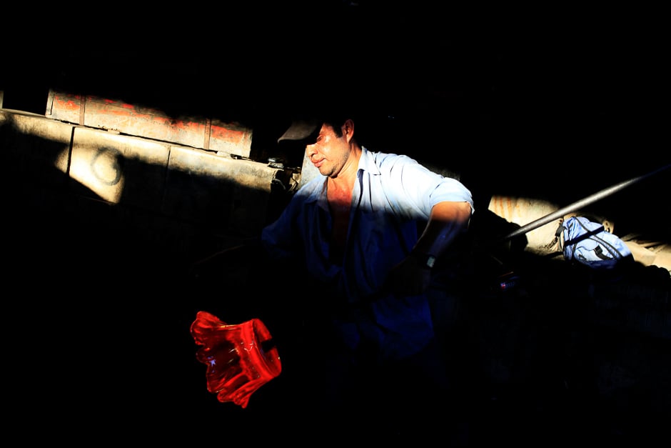 A glassmaker forms molten glass next to a furnace at Cespedes factory in Olocuilta, El Salvador. PHOTO: REUTERS