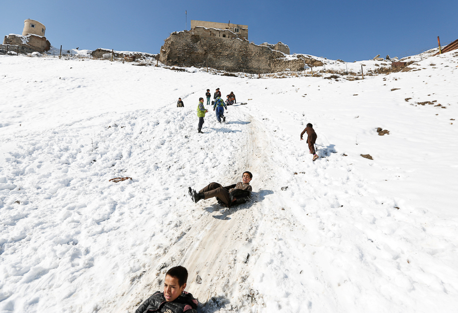 Afghan boys slide down a snow-covered slope in Kabul, Afghanistan. PHOTO: REUTERS