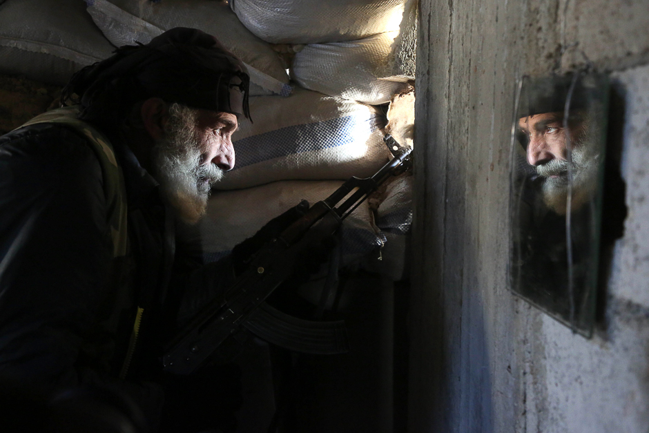 Syrian Mahmoud Al-Khatib, a fighter from the Jaish al-Islam (Islam Army), the foremost rebel group in Damascus province who fiercely oppose both the Syrian regime and the Islamic State group, holds a position inside a building on the frontline in the town of Bilaliyah, east of the capital Damascus. PHOTO: AFP