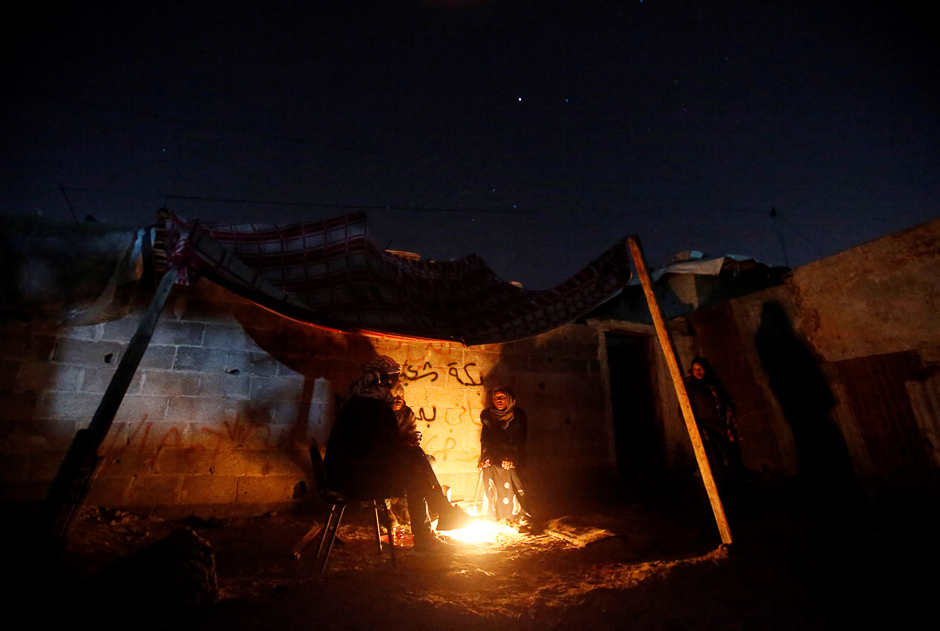 Members of a Palestinian family warm themselves by a fire outside their shelter in the northern Gaza Strip. PHOTO: REUTERS