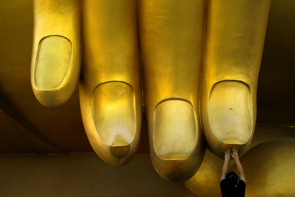 A woman prays while touching the fingers of a Buddha statue during the annual Makha Bucha Day, which celebrates Buddha's teachings, in Ang Thong, Thailand. PHOTO: REUTERS