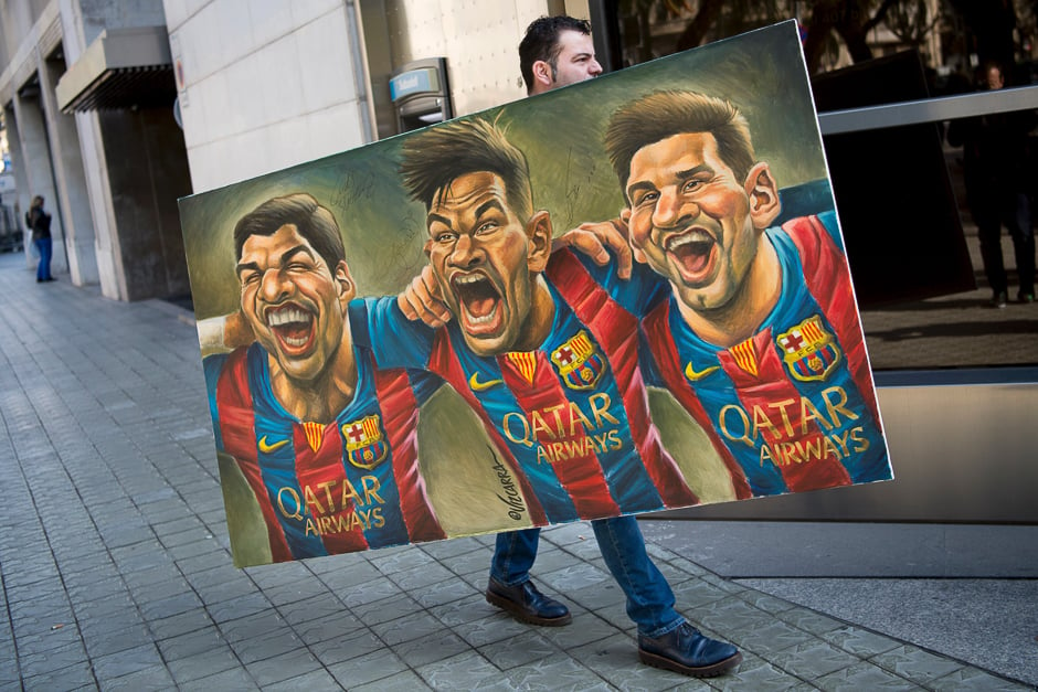 A man carries a painting representing Spanish Barcelona's Uruguayan forward Luis Suarez (L), Barcelona's Brazilian forward Neymar and Barcelona's Argentinian forward Lionel Messi (R) painted by Spanish cartoonist Vizcarra to the presentation of the 12th edition of the book entitled 