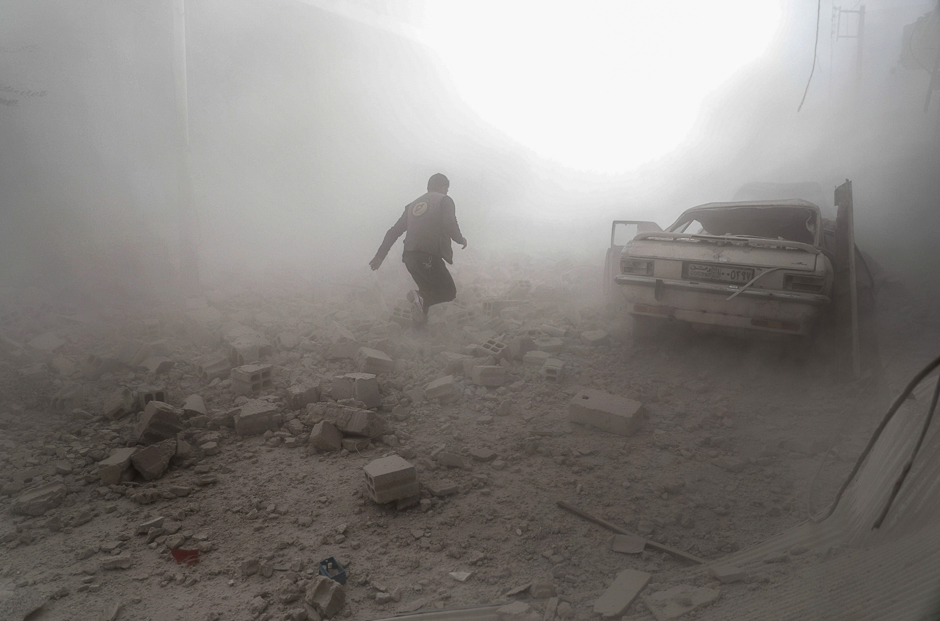 A Syrian Civil Defence volunteer, also known as the White Helmets, runs amid the smoke and dust in search for survivors following reported government airstrike on the rebel-held town of Douma, on the eastern outskirts of the capital Damascus. PHOTO: AFP