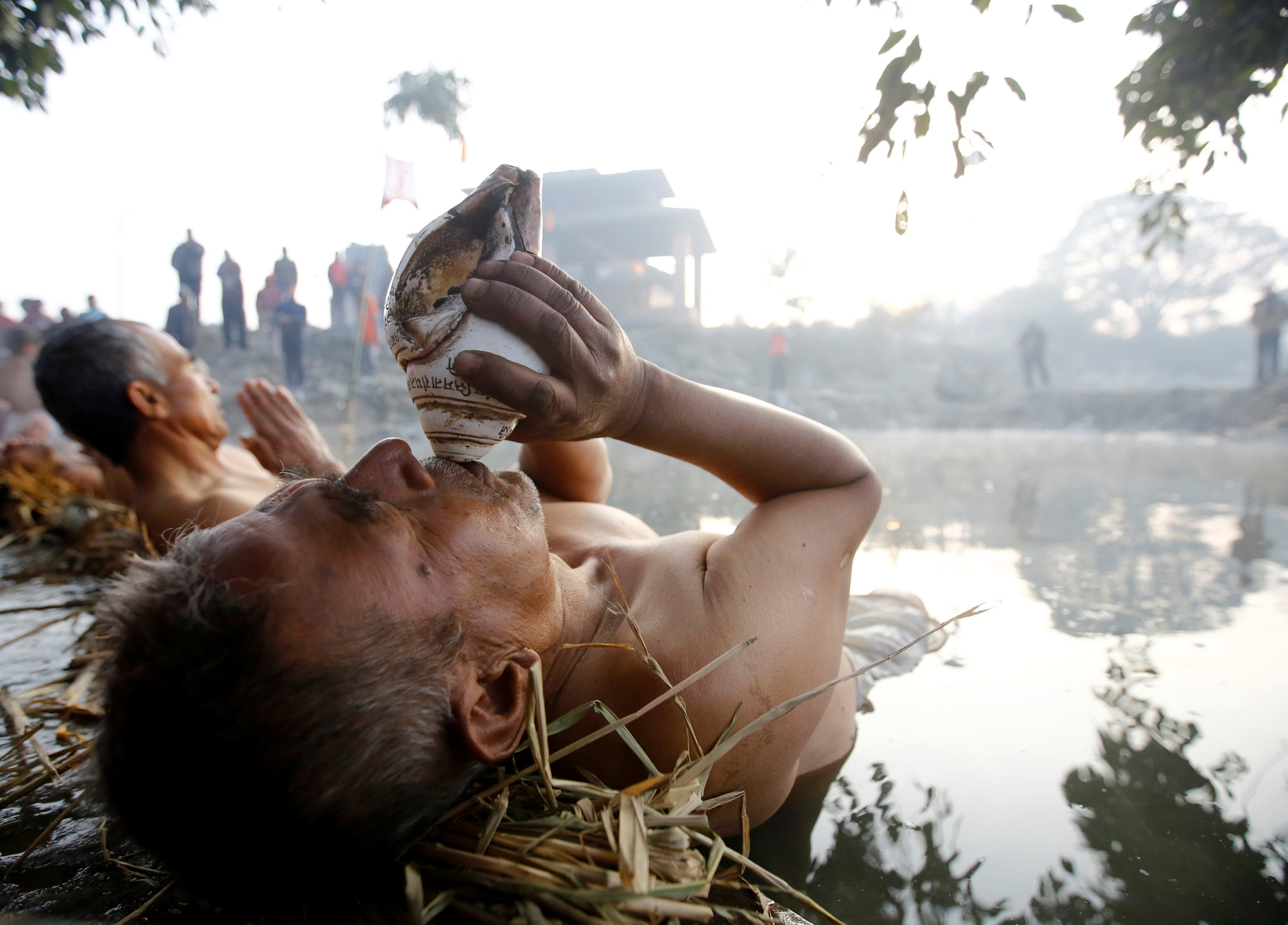 A devotee blows a conch as he offers prayer by submerging in the Hanumante River during the Swasthani Brata Katha festival in Bhaktapur, Nepal January 13, 2017. REUTERS/Navesh Chitrakar