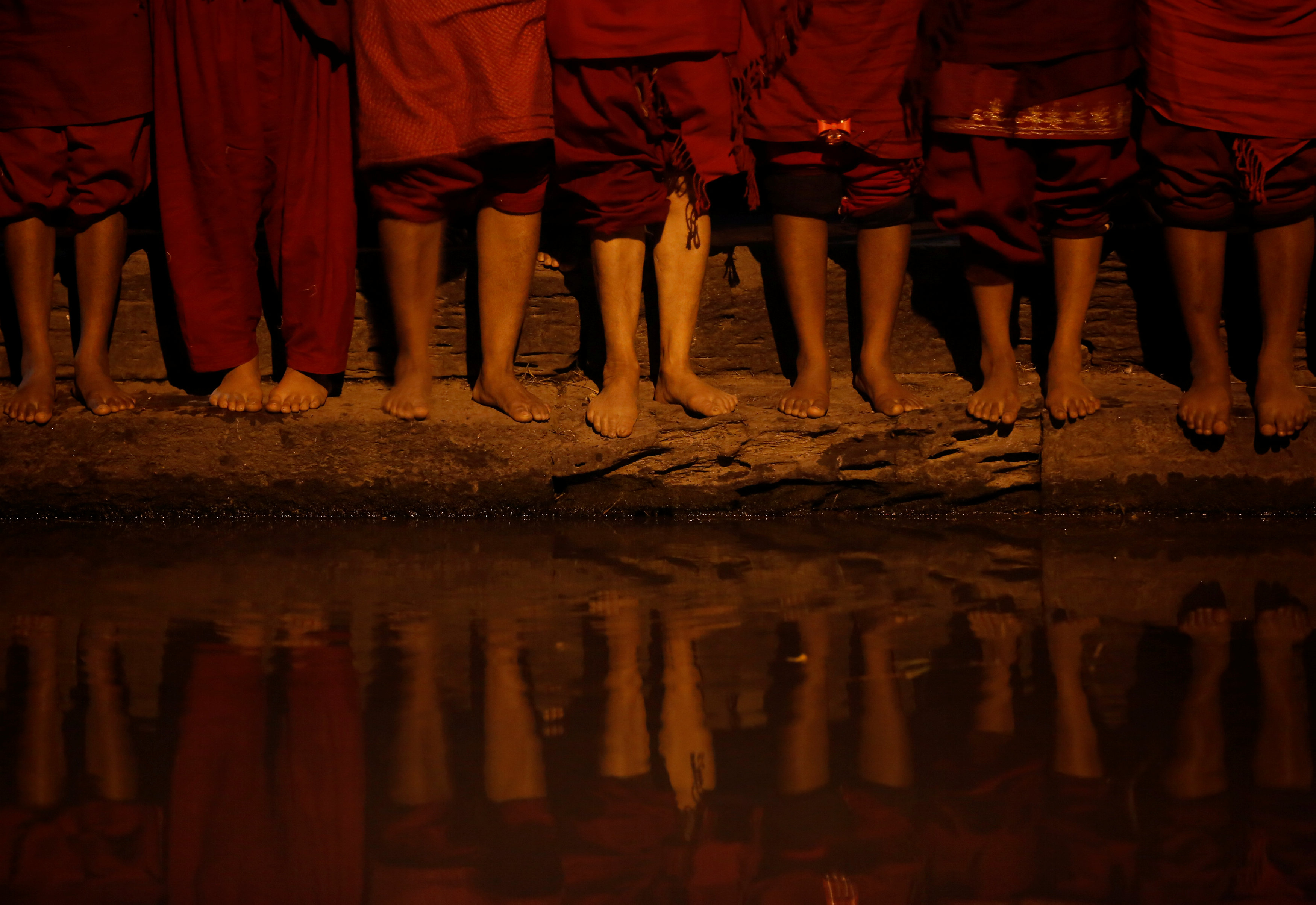 The feet of devotees are pictured as they stand on the banks of the Bagmati River during the Swasthani Brata Katha festival in Kathmandu, Nepal, January 27, 2017. REUTERS/Navesh Chitrakar