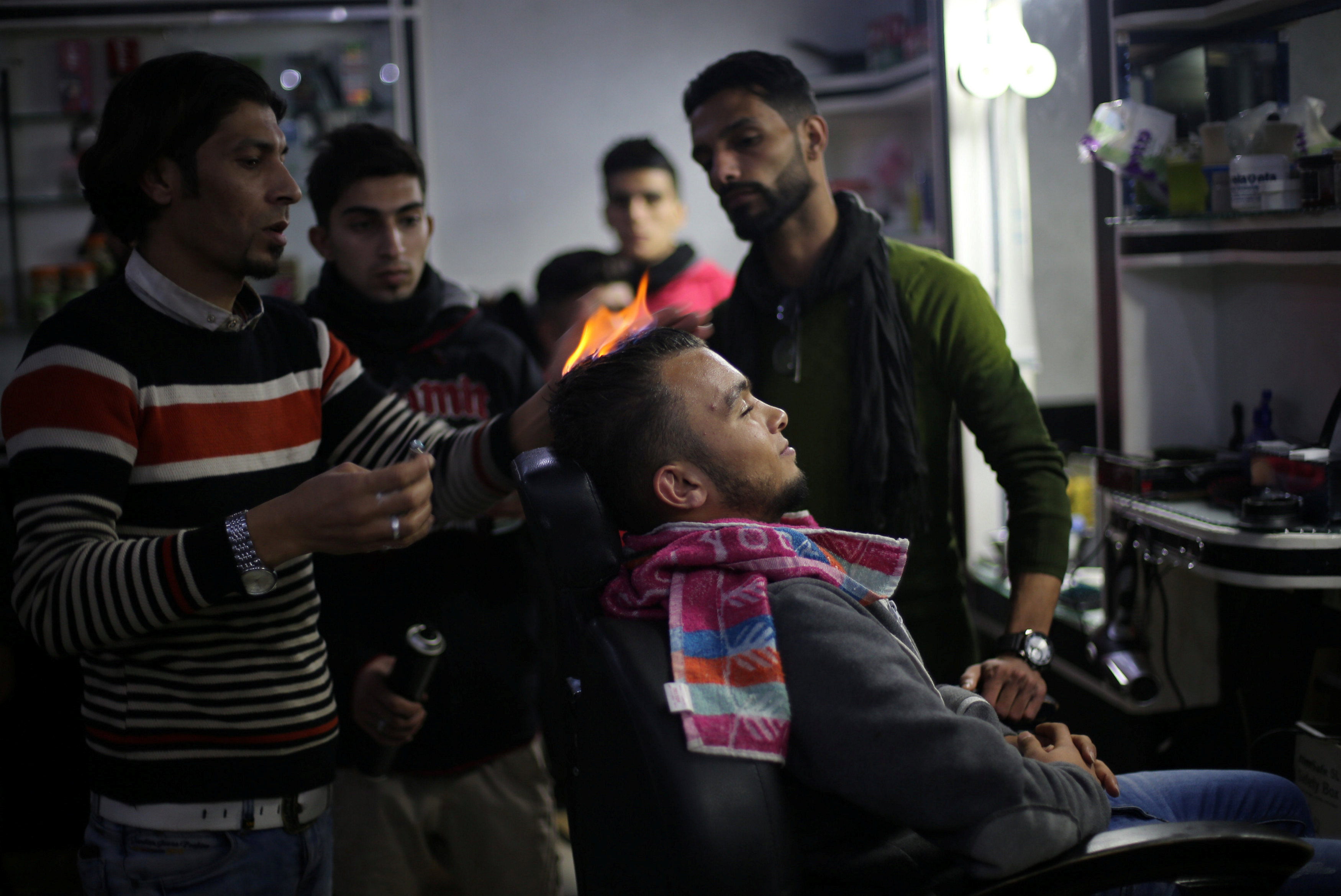 Ramadan Edwan, a Palestinian barber, uses fire in a hair-straightening technique with a client at his salon in the Rafah refugee camp, in the southern Gaza Strip. PHOTO: REUTERS