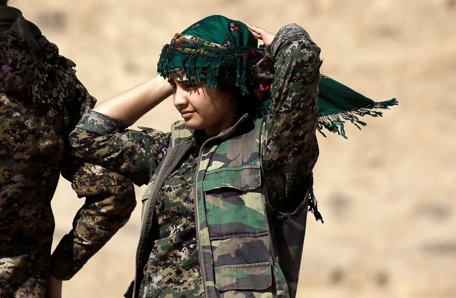 A female Kurdish fighter and member of the US-backed Syrian Democratic Forces (SDF), made up of an alliance of Arab and Kurdish fighters, adjusts her head scarf in the village of Sabah al-Khayr on the northern outskirts of Deir Ezzor as they advance to encircle the Islamic State (IS) group bastion of Raqa. PHOTO: AFP
