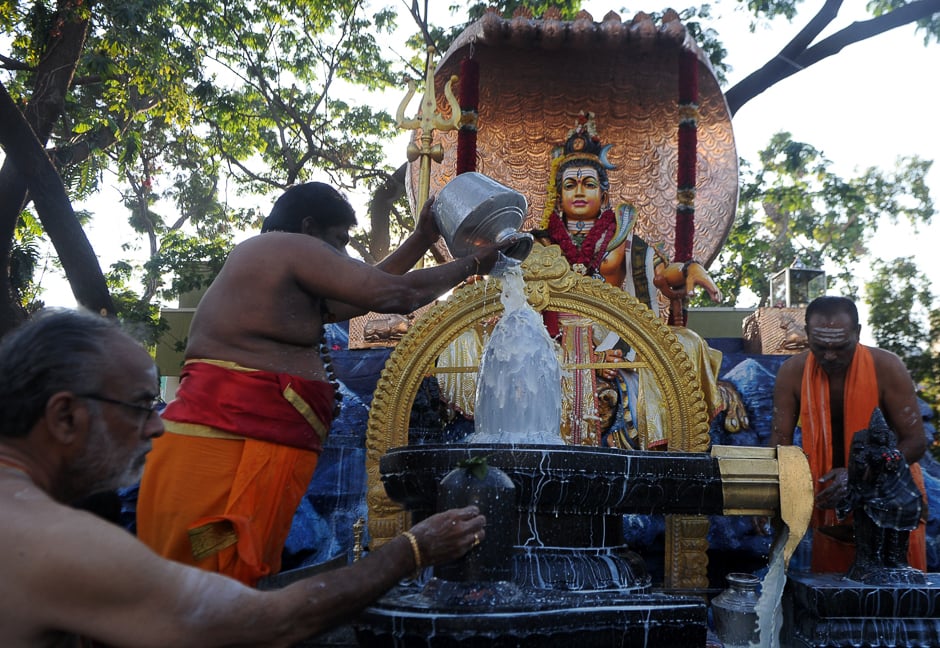 An Indian priest pours milk ocer a Shiva Lingam, a stone sculpture representing the phallus of Hindu god Lord Shiva. PHOTO: AFP