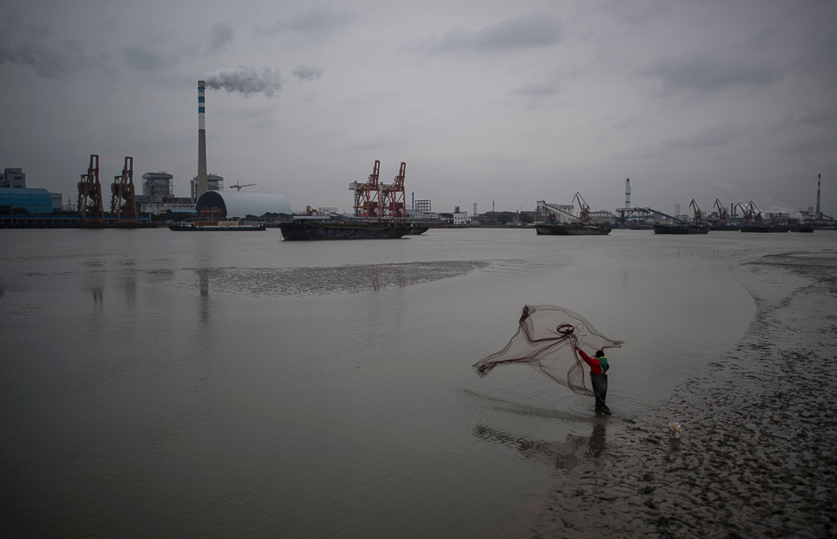 A man catches fish with a net in the Huangpu river across the Wujing Coal-Electricity Power Station in Shanghai. PHOTO: AFP