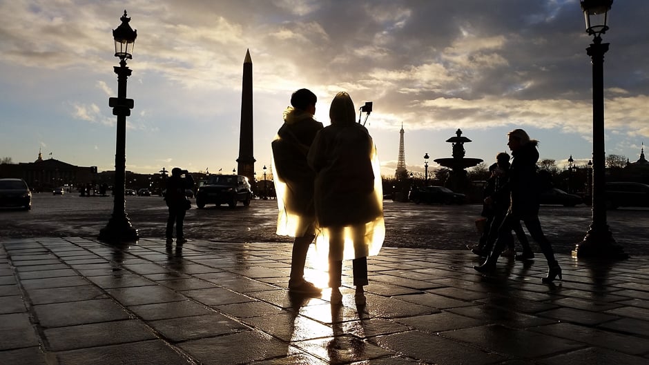 Tourists wearing plastic raincoats take a selfie in the sun after the rain at Place de la Concorde. PHOTO: AFP
