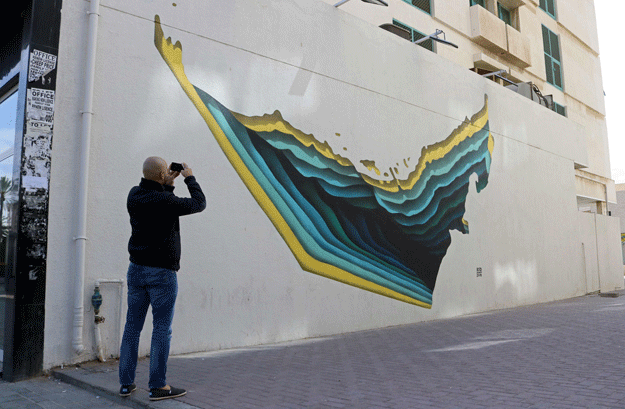 A man takes a picture of graffiti by Tunisian street artist The Inkman on a wall of Dubai's 2nd of December street, which is part of the government-funded Dubai Street Museum project, on February 6, 2017. PHOTO: AFP 