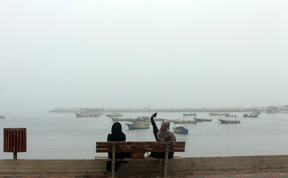 Palestinian women take a selfie in Gaza City's seaport during heavy fog. PHOTO: AFP