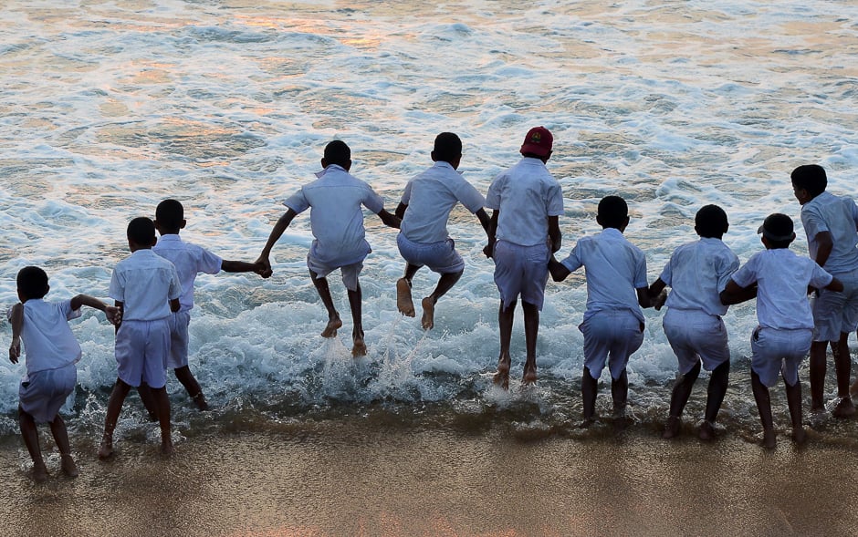 Sri Lankan schoolchildren play at the water's edge on a beach during sunset in Colombo. PHOTO: AFP