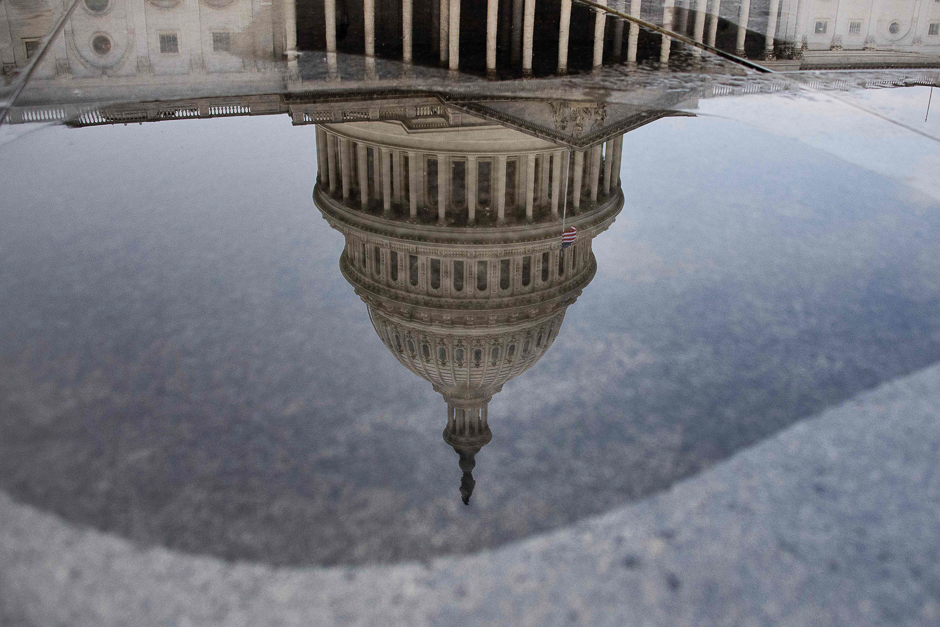 The National Capitol is reflected upside down in a puddle of water in Washington, DC. PHOTO: AFP