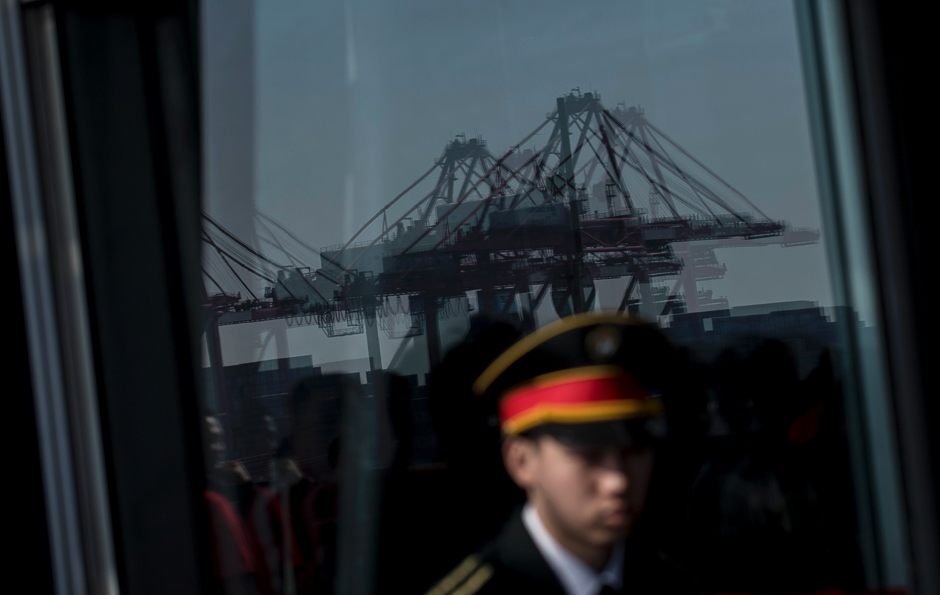 A security guard stands in front of a window reflecting the Yangshan Deep Water Port, part of the Shanghai Pilot Free Trade Zone in Shanghai. PHOTO: AFP