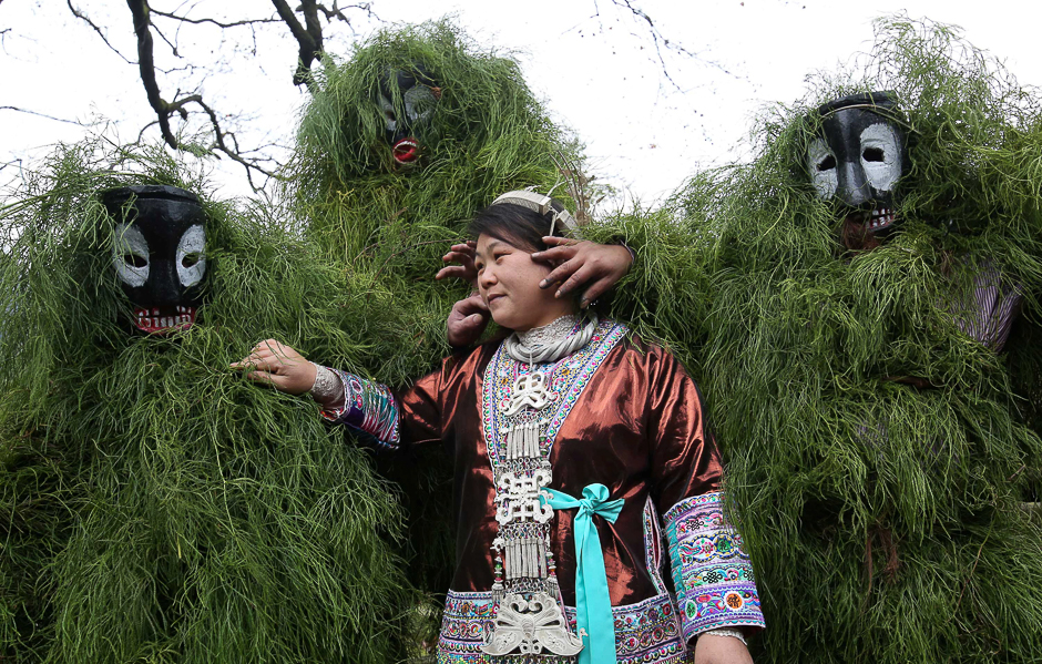 Ethnic Miao men wearing traditional masks smear dust on a woman's face to wish her good luck during a local celebration event for Lunar New Year in Liuzhou, Guangxi Zhuang Autonomous Region, China. PHOTO: REUTERS
