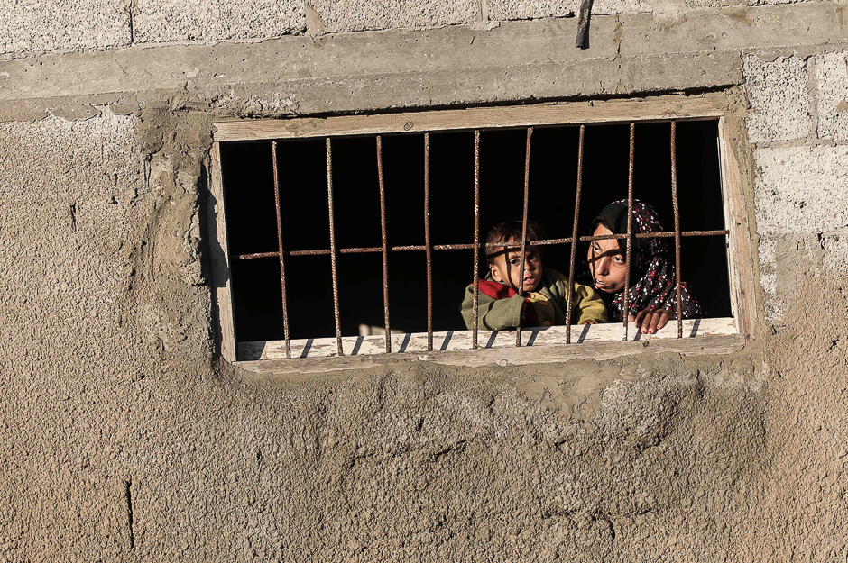 A Palestinian woman peers through the window of her house in an impoverished area in the southern Gaza Strip town of Khan Yunis. PHOTO: AFP