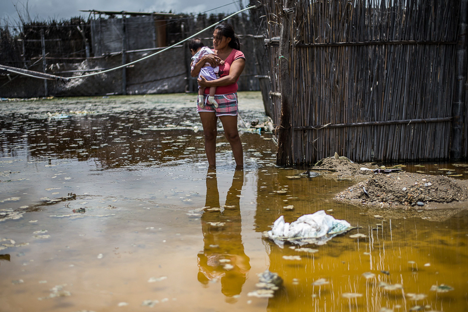 A woman and her baby stand in a flooded street, in the province of La Union in Piura, northern Peru. PHOTO: AFP