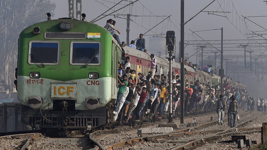 Indian passengers hang onto a train as it departs from a station on the outskirts of New Delhi. PHOTO: AFP