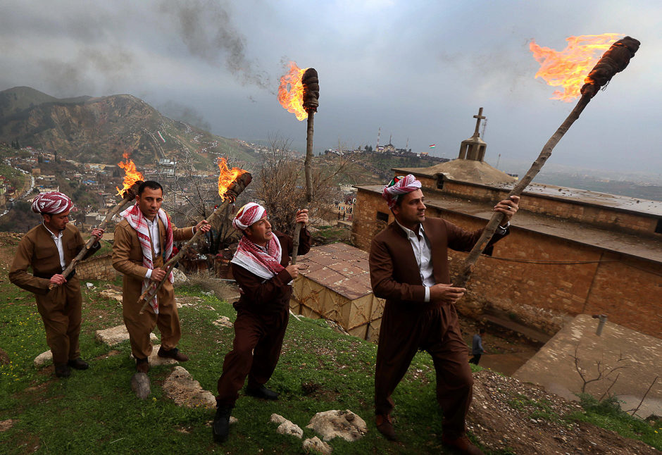 Iraqi Kurds holding lit torches walk up a mountain, draped in a large Kurdish flag, in the town of Akra, 500 km north of Baghdad as they celebrate the Noruz spring festival. PHOTO: AFP