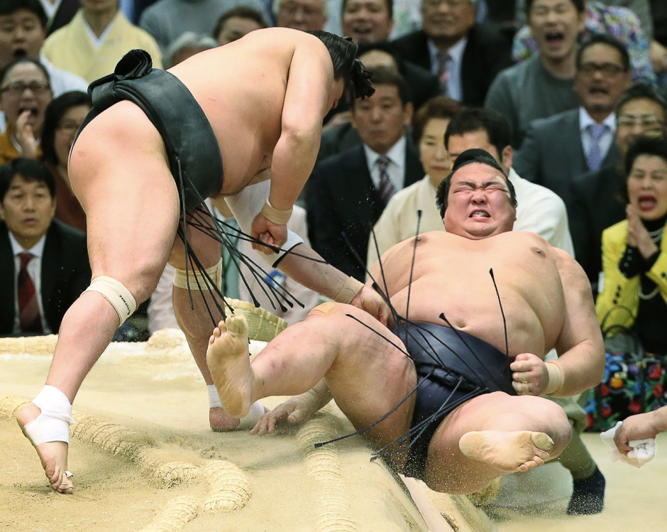 Japanese Yokozuna or sumo grand champion Kisenosato (R) is thrown out of the ring by Mongolian Yokozuna Harumafuji (L) at the Spring Grand Sumo Tournament in Osaka. PHOTO: AFP