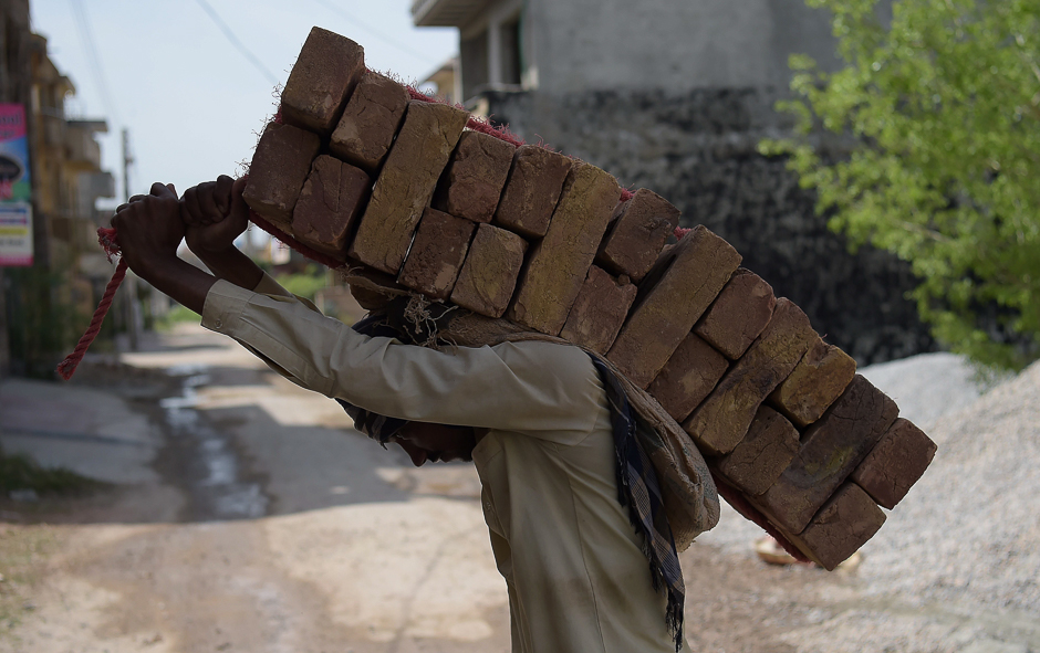 A Pakistani labourer carries bricks on his back at a construction site at a residential area in Islamabad. PHOTO: AFP