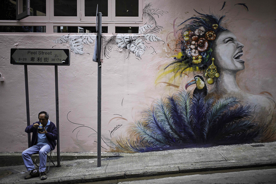 A man eats a meal beside street art painted on a shoplot wall along Peel Street in Hong Kong's SoHo district. From graffiti shows to major installations, Hong Kong will see a creative surge as Art Basel comes to town this week, but residents want a more permanent change to the visual landscape. PHOTO: AFP