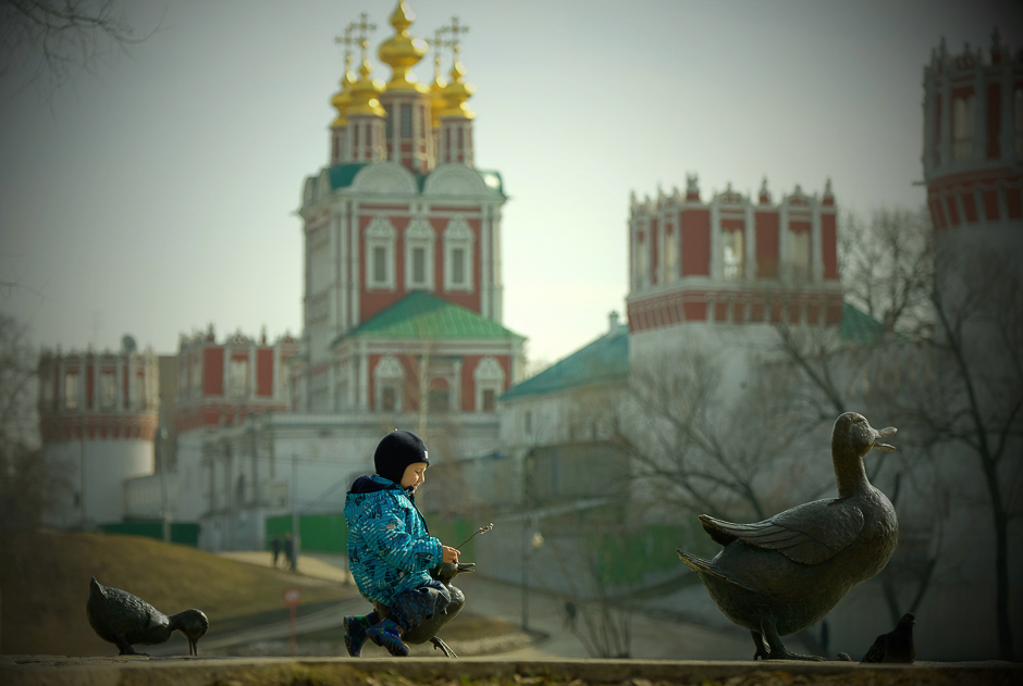 A boy plays on a sculpture of a duck and ducklings, with Moscow's Novodevichy Convent seen in the background. PHOTO: AFP