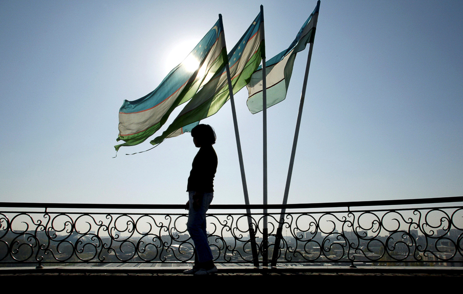 A girl is silhouetted against the sun standing next to Uzbek flags in Tashkent. PHOTO: REUTERS