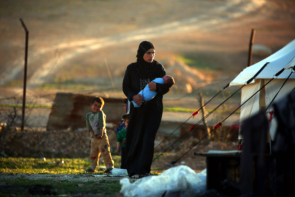 A Syrian woman carries her child at a temporary refugee camp in the village of Ain Issa, housing people who fled Islamic State group's Syrian stronghold Raqa, some 50 kilometres (30 miles) north of the group's de facto capital. PHOTO: AFP
