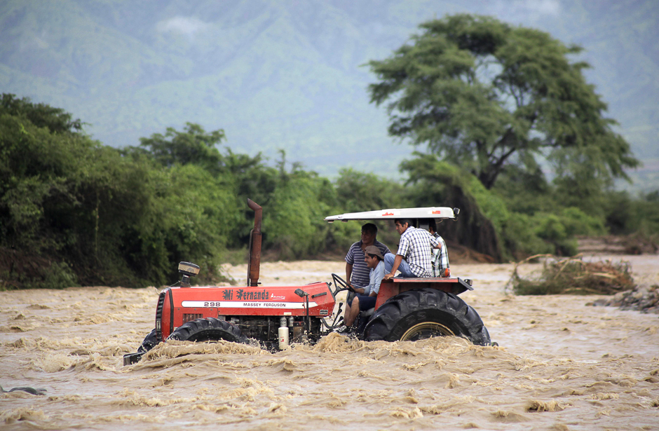 People who live in the countryside outside the town of Chiclayo, 770 kilometres north of Lima, use a tractor to cross the rising waters of the Zana River. PHOTO: AFP